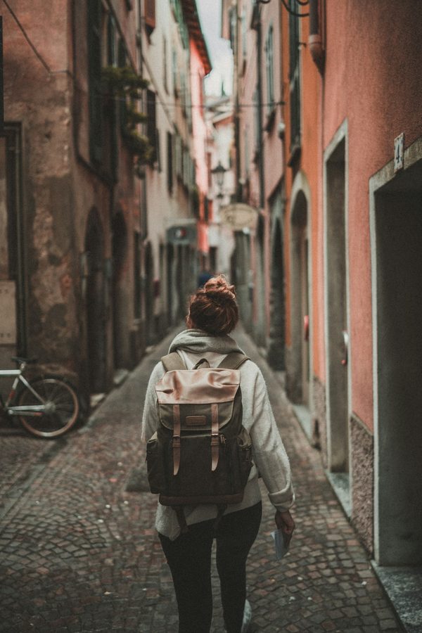 Pessoa de mochila caminhando por uma viela estreita